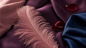 Editorial flat-lay featuring Womanizer Premium 2 and Duo 2, purple silk, pink feather
