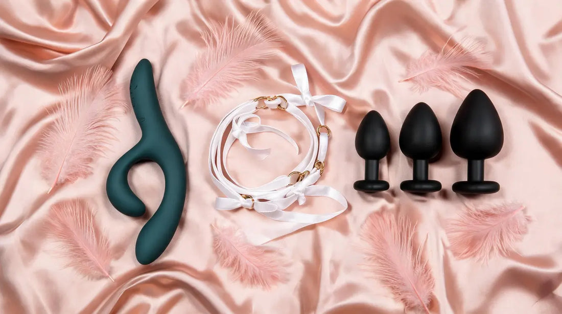 Curated date night kit — We-Vibe Nova 2, satin ribbon harness, and training plug trio on blush silk