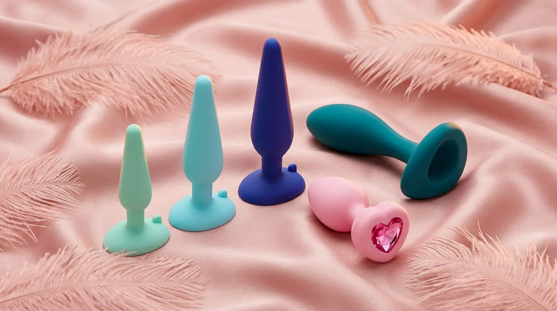 b-Vibe anal wellness products on blush silk with feathers