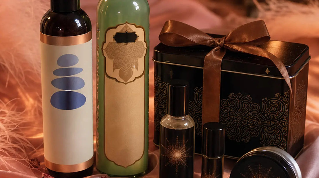 Massage oil bottles and a pheromone gift set with candle arranged on dusty-rose silk satin with pink feathers, dried rose petals, and warm candlelight