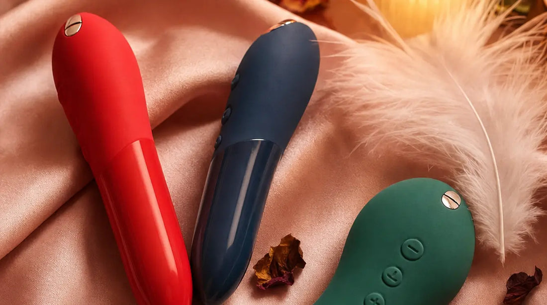 We-Vibe Tango X Cherry, Tango X Midnight Blue, and Touch X Green Velvet on blush pink silk satin with feathers and candlelight
