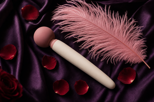 Editorial flat-lay of an unbranded soft personal massager wand on aubergine silk with pink feather and rose petals