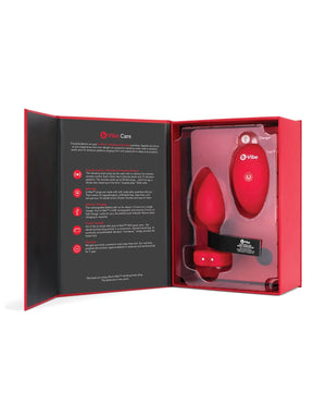 Red electronic anal plug device in a open box with Vibe Care branding on a white background