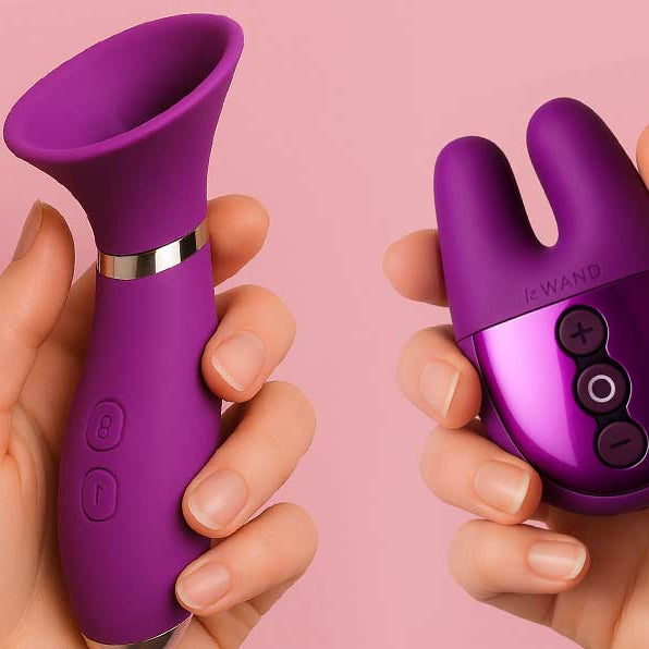Two purple silicone products held by hands against a pink floral background